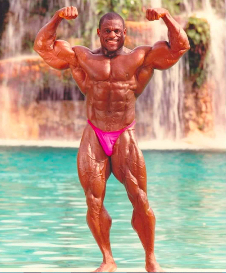 Vince Taylor flexing biceps in front of water