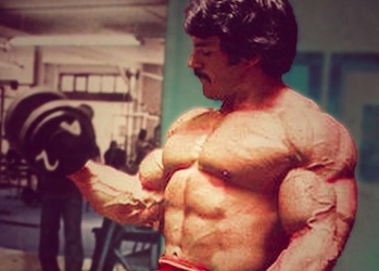 Cropped pic of Mike Mentzer doing alternate dumbbell curls, looking incredible