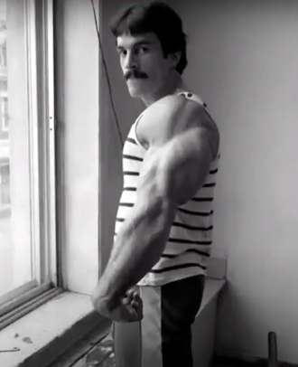 Mike Mentzer at a window showing his triceps mass