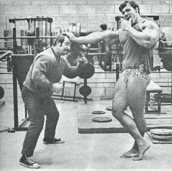 Arnold holding back a guy in the gym